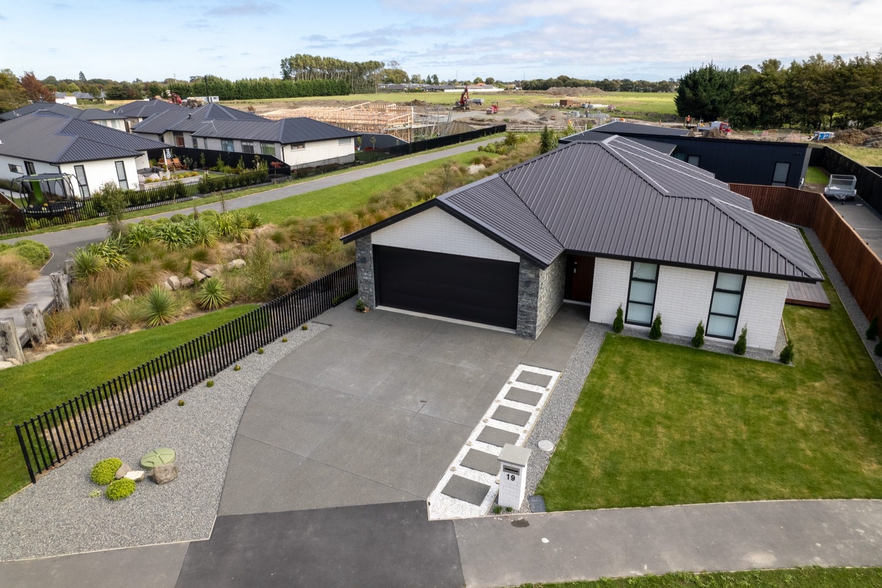 Aerial view of the Milns Park house on its section, showing the planted reserve and walkway running along the boundary and open land beyond.