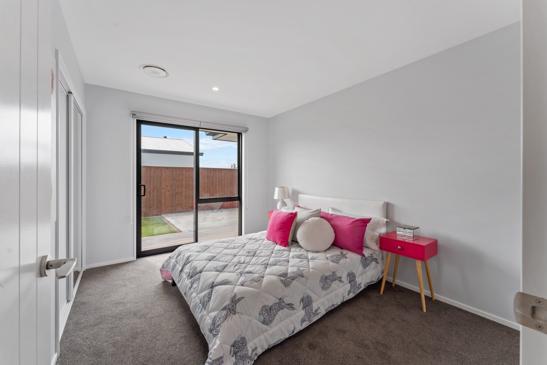 Bedroom at Milns Park with a sliding door to the deck and mirrored wardrobe doors.
