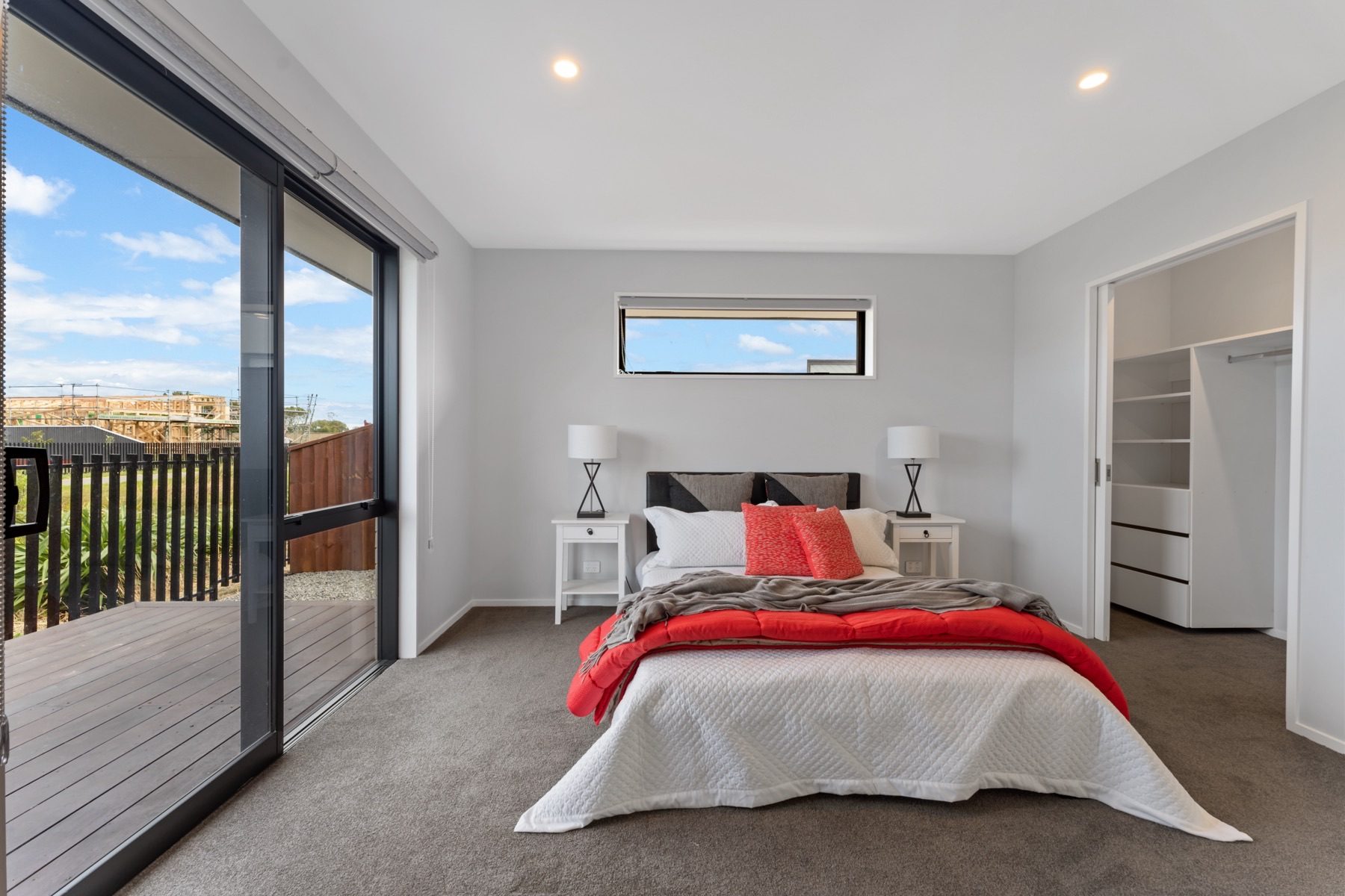 Bedroom with its own sliding door onto the deck and a walk-in wardrobe fitted with shelving and drawers.