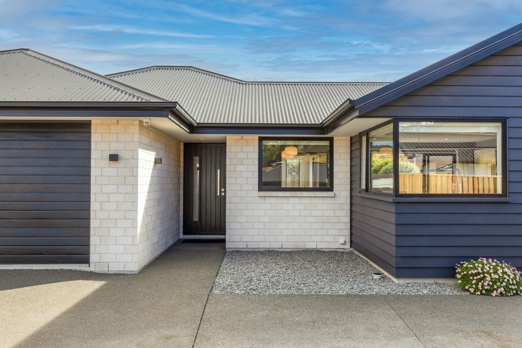 The entry to the Old Stone Lane home: a dark vertical-board front door with a slot window, set between pale block and dark weatherboard.