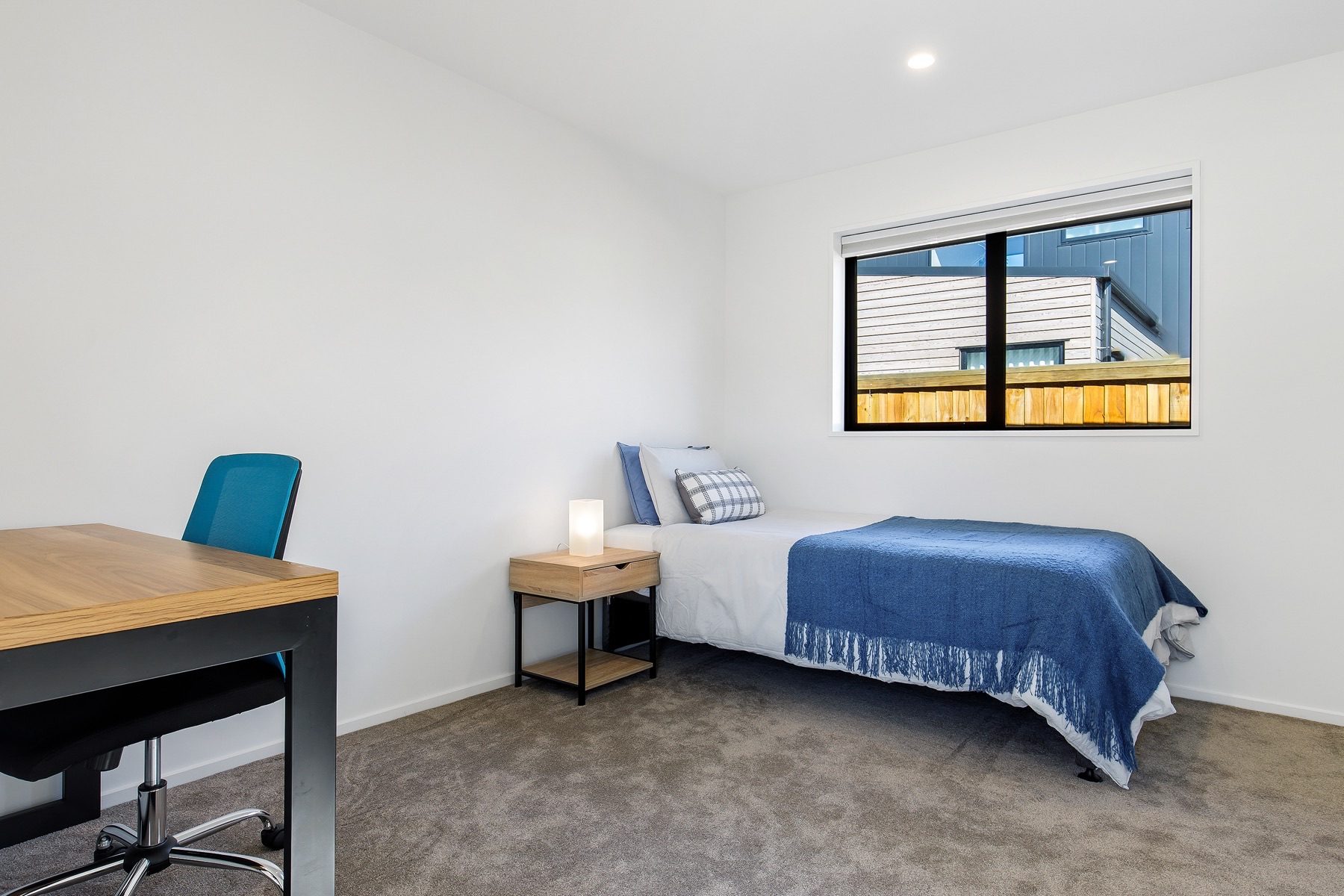 Bedroom fitted out as a study, with a desk under the window and a single bed against the wall.
