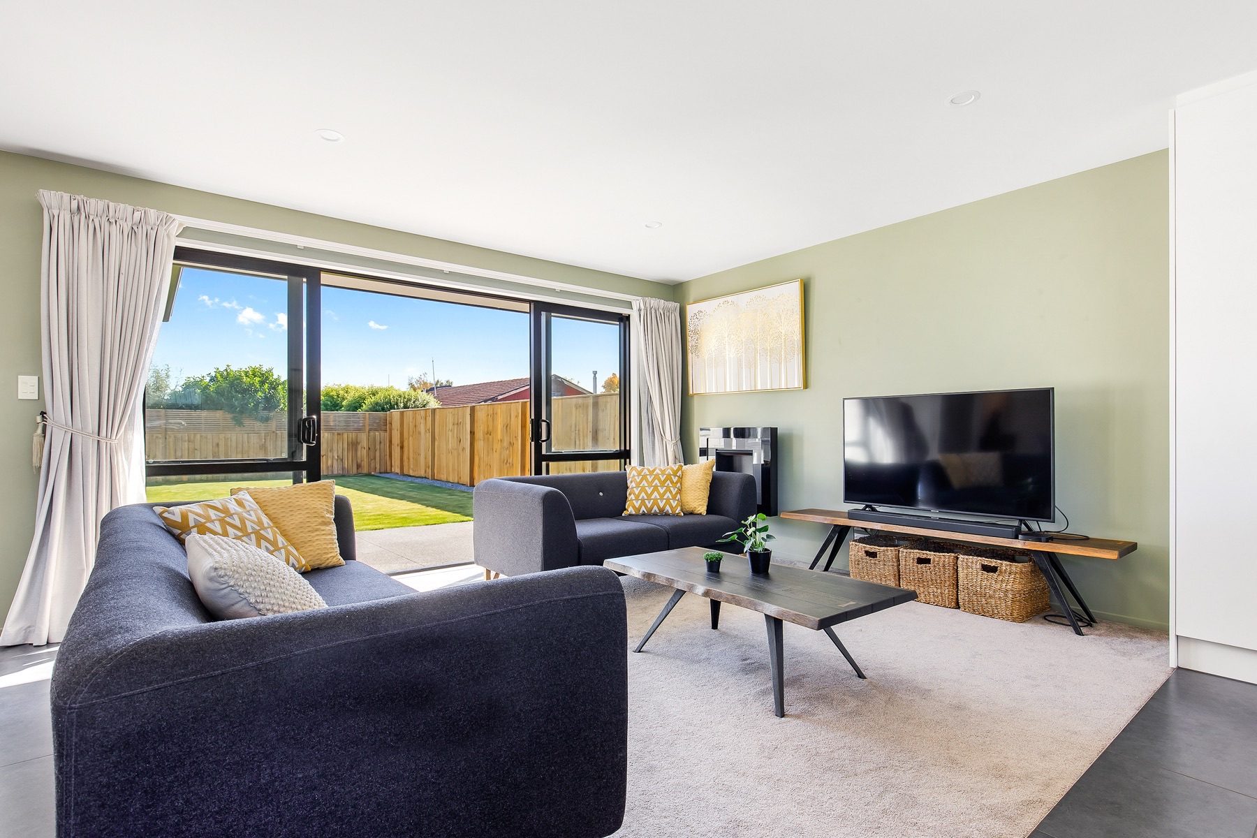 The separate living room, with sage-green walls and sliding doors opening onto the lawn.