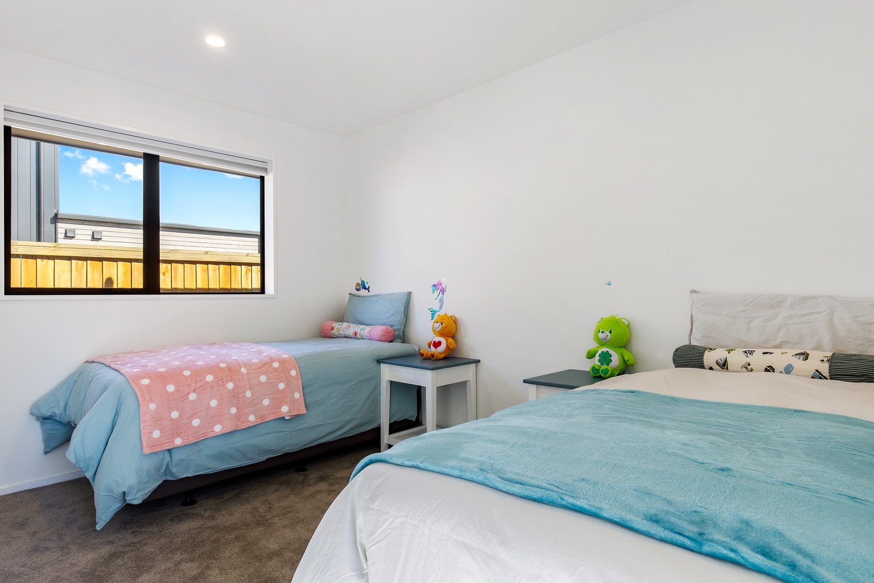 A children's bedroom at Old Stone Lane, carpeted, with a window to the boundary fence.