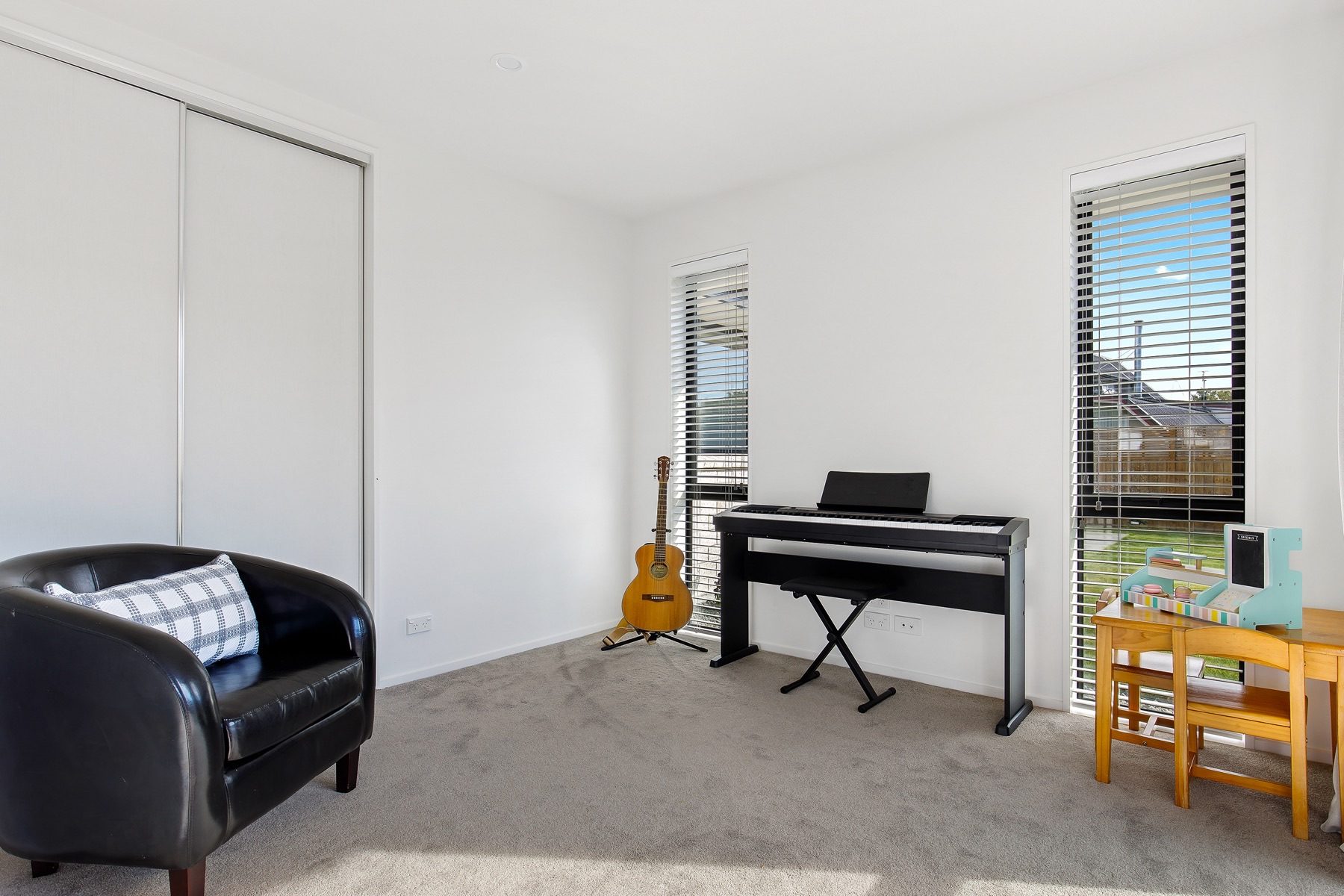 The media room, carpeted and fitted with a sliding-door wardrobe, lit by two tall windows.