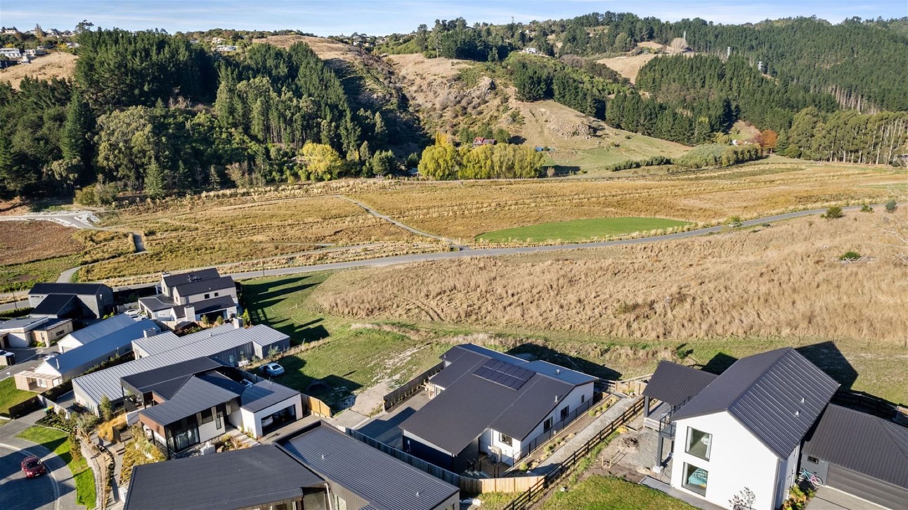 The house seen from above in its Cracroft valley setting, with the Port Hills rising behind and open paddock opposite.