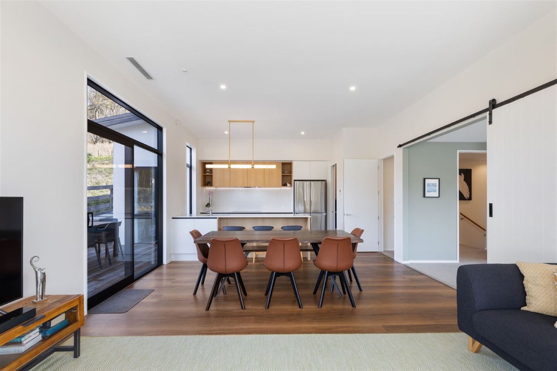 View across the kitchen island toward the dining area and the glazed corner beyond.