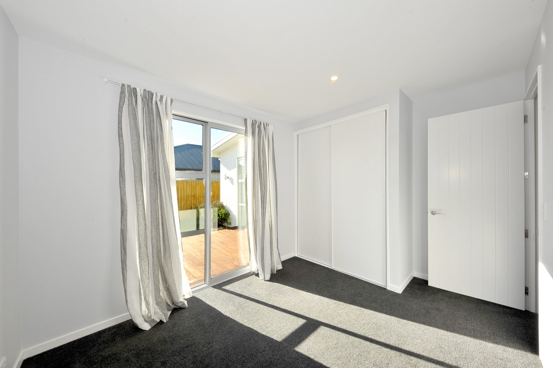 Bedroom opening onto the deck through a sliding door, with a built-in wardrobe along the far wall.