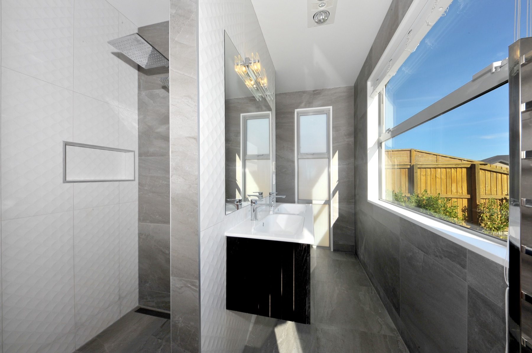 The fully tiled ensuite, with a double vanity, a heated towel rail and a walk-in shower under twin rain heads.