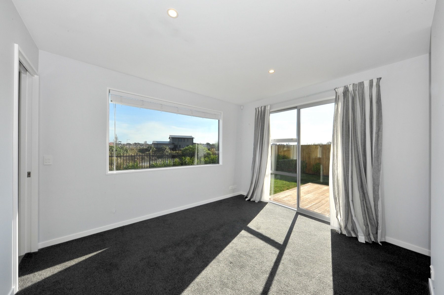 Bedroom with a wide picture window to the waterway planting and a sliding door onto the deck.