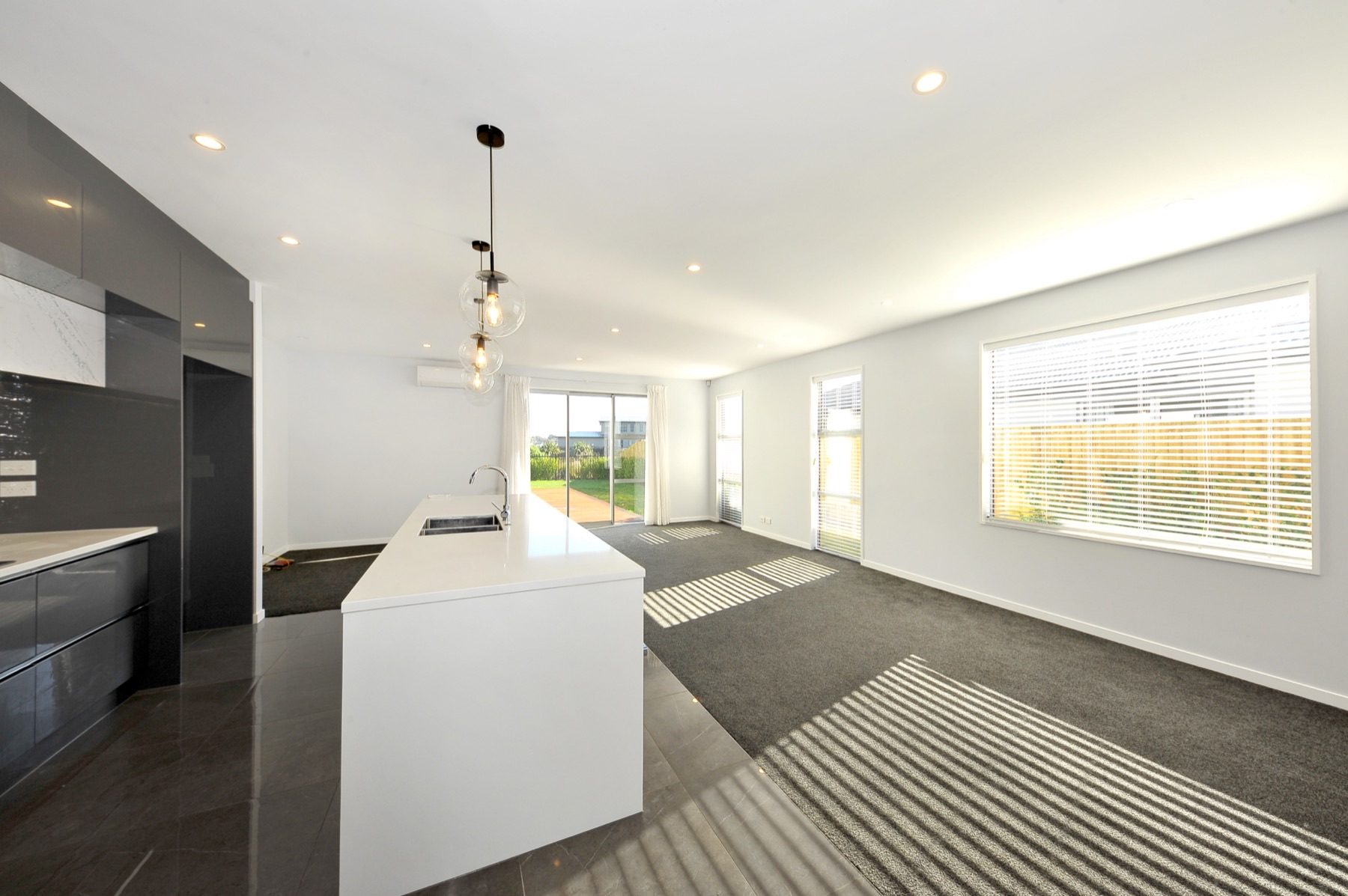 Living and dining at Vernon Drive looking back toward the kitchen island, with sliding doors to the deck and lawn.