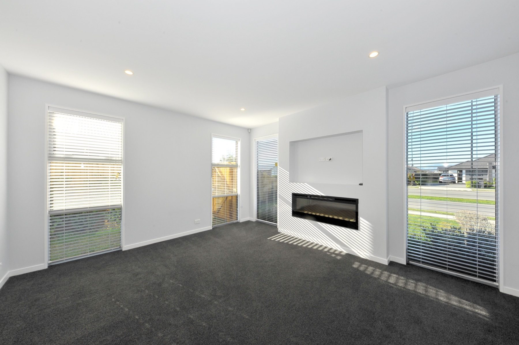 The separate lounge, with a linear gas fire recessed into a white wall below a television niche and tall windows to the street.