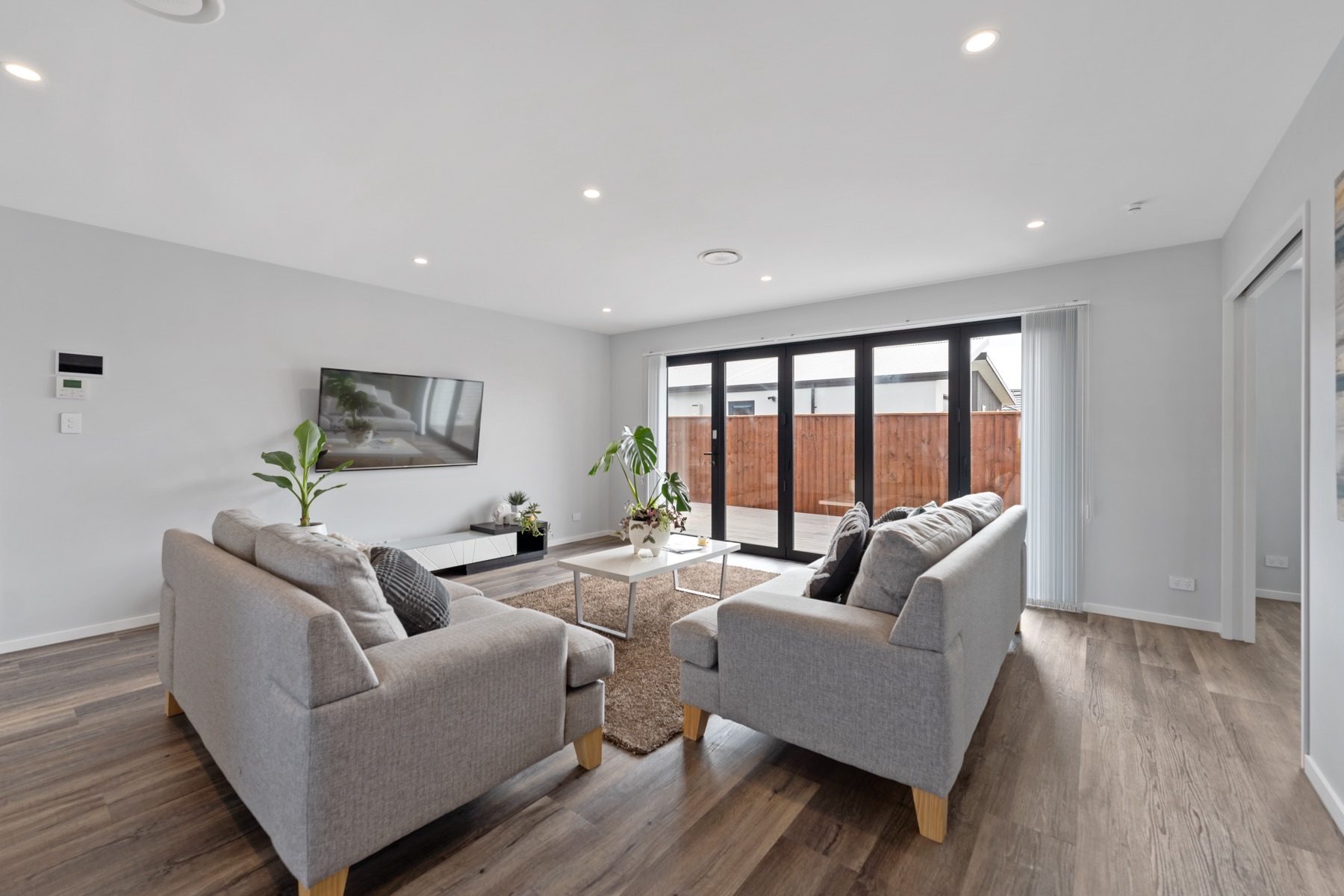 Living room in a JSR-built home at Milns Park, with bi-fold doors opening onto the timber deck.