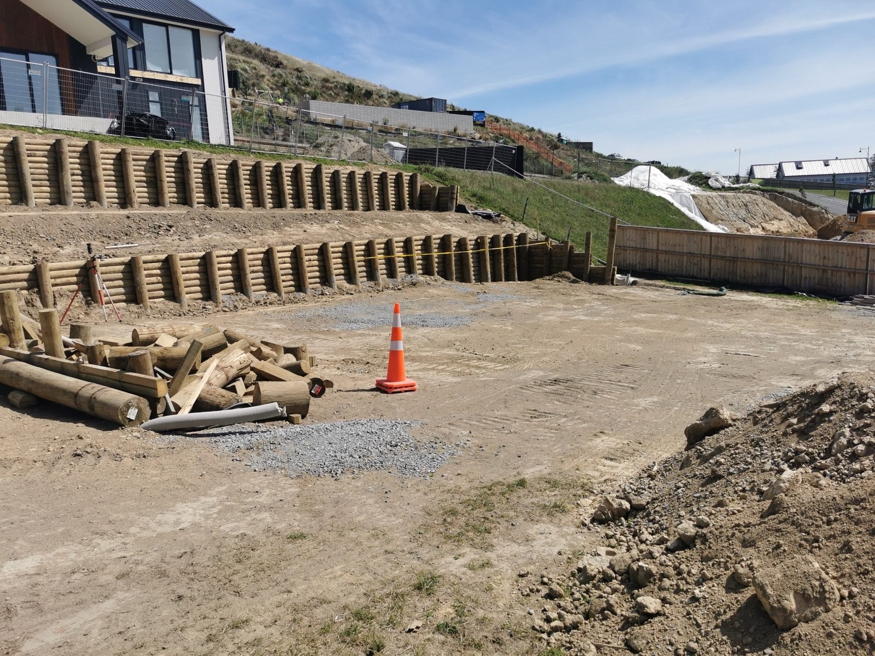 The excavated hillside platform at Round Hill Rise, held by two tiers of timber pole retaining stepping up the slope.