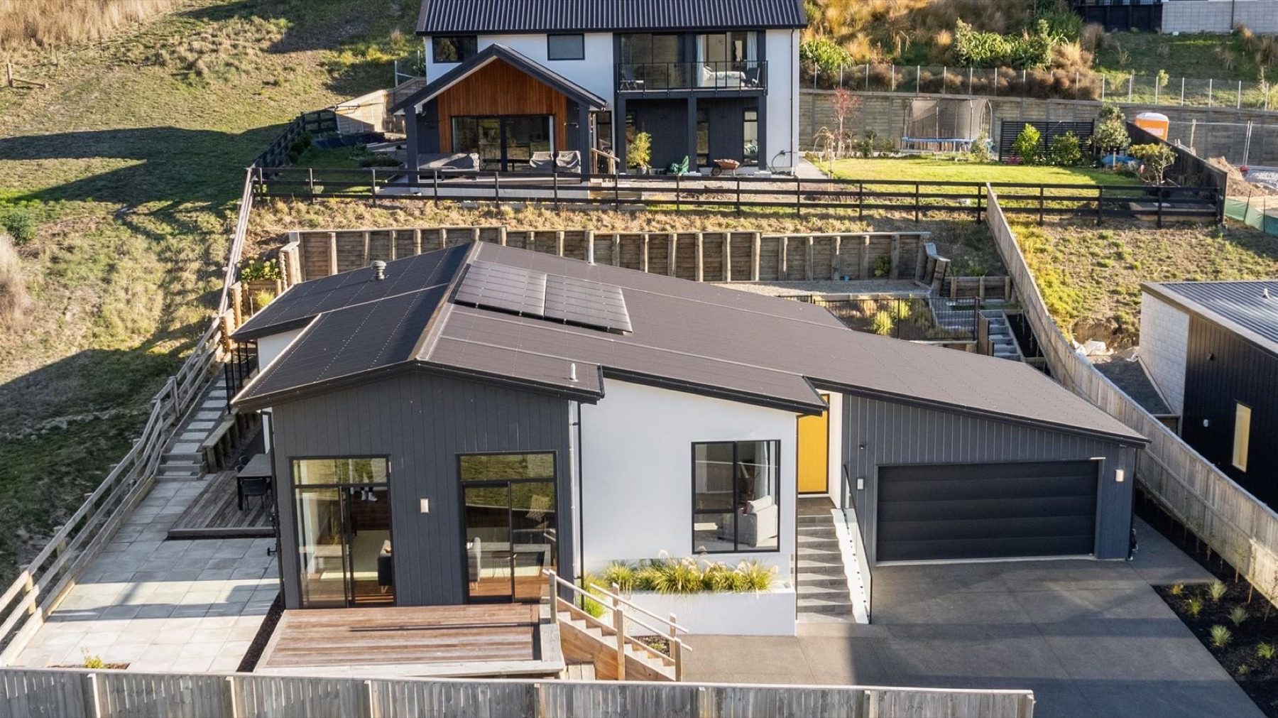 The completed Round Hill Rise house on the same platform, roof planes and terrace visible from above.